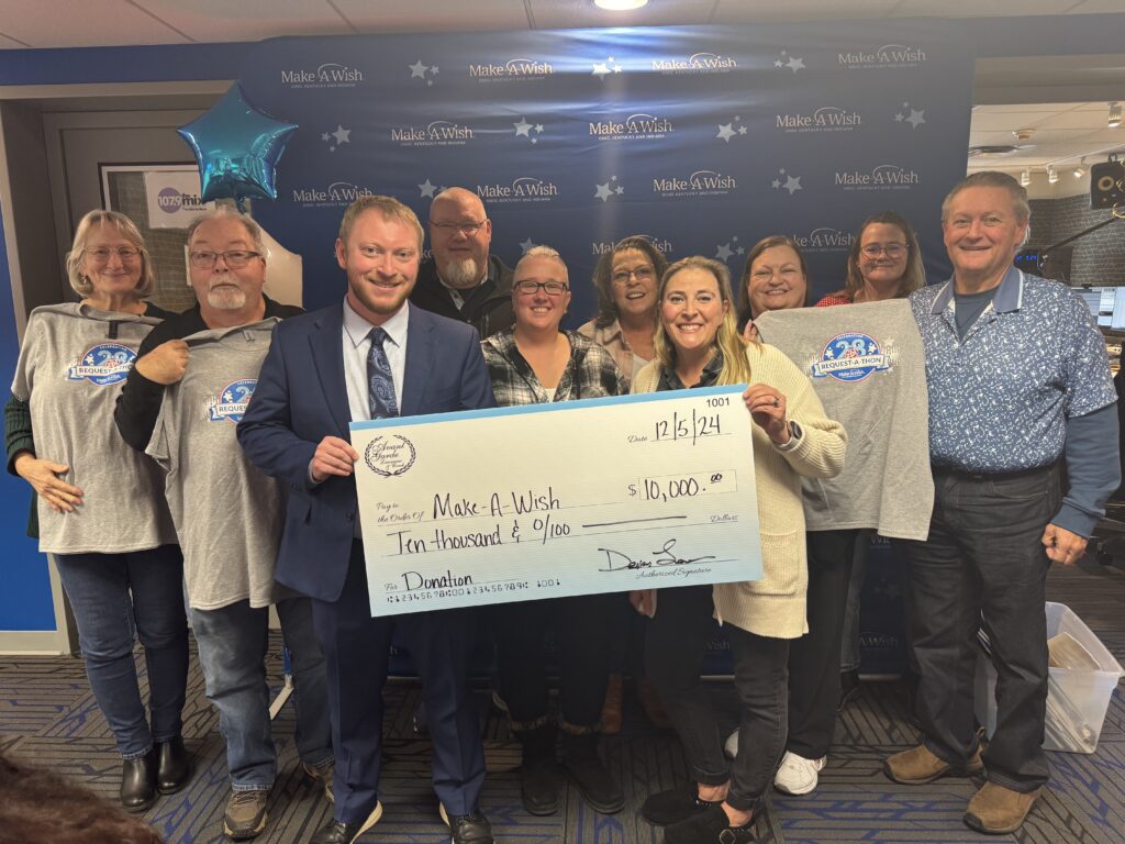 Denny Leinhos holding a check for a make a wish foundation donation